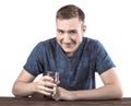 A young man in a dark blue T-shirt is holding a glass of water in his hand, on a white background.