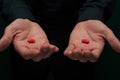 Young man in a dark shirt holding two red pills