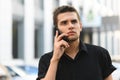 Young man in a dark shirt with a serious face talks on the phone and looks away. Concentrated young businessman talking on the Royalty Free Stock Photo