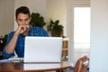 Young man deep in thought while working remotely from home