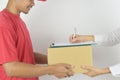 Young man delivering package to customer at home. Woman receiving a package from the courier and signing the form close-up Royalty Free Stock Photo