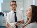 Young man dentist in white coat show veneers enamel color palette for beautiful patient woman Royalty Free Stock Photo