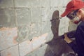 Young man dismantles an old tile from a concrete wall