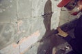 young man dismantles an old tile from a concrete wall