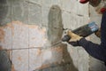 Young man dismantles an old tile from a concrete wall