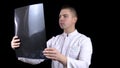 A young man doctor checks the results of an MRI scan of a spine. A man examines an MRI image then shows a thumb down