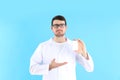 Young man doctor holds bottle of pills on blue background Royalty Free Stock Photo