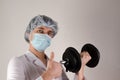 Young man doctor keep dambbell in a hand and show like on neutral background. Medcine and sport concept. Royalty Free Stock Photo