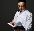 Young man doctor read book. Medicine worker. Healthcare concept on dark