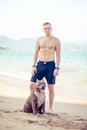 Young man with dog american pit bull terrier posing on the tropical beach Royalty Free Stock Photo