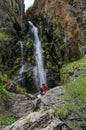 Young man and dog sitting in front of a waterfall