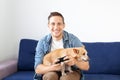 Young man with dog sitting on sofa and holding joystick. Close-up of an attractive bristle guy holding a joystick playing games on