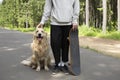 A young man and a dog on a skateboard ride in the park in the summer Royalty Free Stock Photo