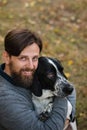 Young man with dog walks in autumn park. He hugged his pet. Dog is hunting, short-footed, lop-eared and spotty. Outbred dog Royalty Free Stock Photo