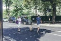 A young man with a dog and a woman crossing Grove End Road in St John's Wood, City of Westminster, London