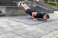 Young man doing a decline push-up or elevated push-up on concrete background outdoors