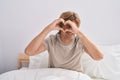 Young man doing heart gesture sitting on bed at bedroom Royalty Free Stock Photo