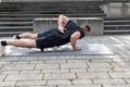 Young man doing a one arm push-up outdoors on concrete background