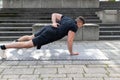 Young man doing a one arm push-up outdoors on concrete background