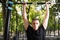 Young man doing pull ups on horizontal bar outdoors, workout, sp Royalty Free Stock Photo