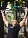 Young man doing pull ups on horizontal bar outdoors, workout, sport concept Royalty Free Stock Photo