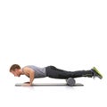 Improving his strength and flexibility. A young man doing push-ups on his exercise mat with his legs raised by a foam Royalty Free Stock Photo