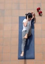 Young man doing sit-ups on mat on terrace outdoor with cap and headphone Royalty Free Stock Photo