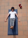 Young man doing sit-ups on mat on terrace outdoor with cap and headphone Royalty Free Stock Photo