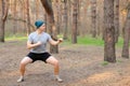 Young man doing workout and squats in morning park.