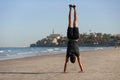 Young man doing yoga exercise - handstand on sandy beach near the sea. Active lifestyle concept. Royalty Free Stock Photo