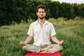 a young man doing yoga in nature with a smile, sitting in the lotus position 2 Royalty Free Stock Photo