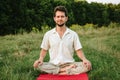 a young man doing yoga in nature with a smile, sitting in the lotus position 1 Royalty Free Stock Photo