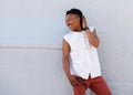 Young man with dreadlocks smiling outside against gray wall Royalty Free Stock Photo