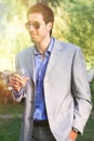 Young man with dress, sunglasses and cocktail in hand. Outdoors aperitivo party