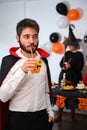 Young man dressed as vampire drinking cocktail at costume Halloween party. Royalty Free Stock Photo