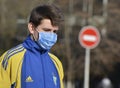 A young man dressed in an ukrainian olympic uniform and in a medical mask on a background of a forbidden entry sign