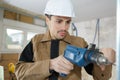 Young man drilling hole in wall Royalty Free Stock Photo