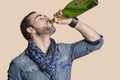 Young man drinking champagne from bottle over colored background Royalty Free Stock Photo