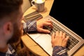 Young man drinking coffee in cafe and using laptop. Man& x27;s hands using laptop during coffee break Royalty Free Stock Photo