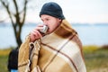 A young man drinking coffee with cup standing on the autumn beac Royalty Free Stock Photo