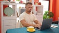 Young man drinking coffee using laptop sitting on table at dinning room Royalty Free Stock Photo