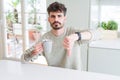 Young man drinking a cup of coffee in the morning with angry face, negative sign showing dislike with thumbs down, rejection Royalty Free Stock Photo