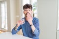 Young man drinking a fresh glass of water cover mouth with hand shocked with shame for mistake, expression of fear, scared in