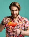 Young man drinking margarita cocktail drink juice happy looking at camera laughing over light blue mint Royalty Free Stock Photo