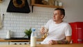 Young man drinking milk in kitchen. Adult male enjoying useful drink for breakfast. Royalty Free Stock Photo