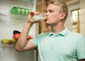 Young man drinking milk in the kitchen, standing at the fridge Royalty Free Stock Photo