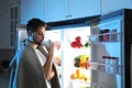 Man drinking milk near open refrigerator at night Royalty Free Stock Photo