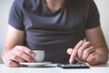 Young man drinking morning coffee and holding mobile phone. Coffee break. Man holding cup of fresh roasted coffee and looking at t