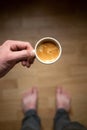 Young man drinking morning coffee and holding mobile phone. Coffee break. Man holding cup of fresh roasted coffee and looking at t