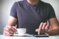 Young man drinking morning coffee and holding mobile phone. Coffee break. Man holding cup of fresh roasted coffee and looking at t Royalty Free Stock Photo